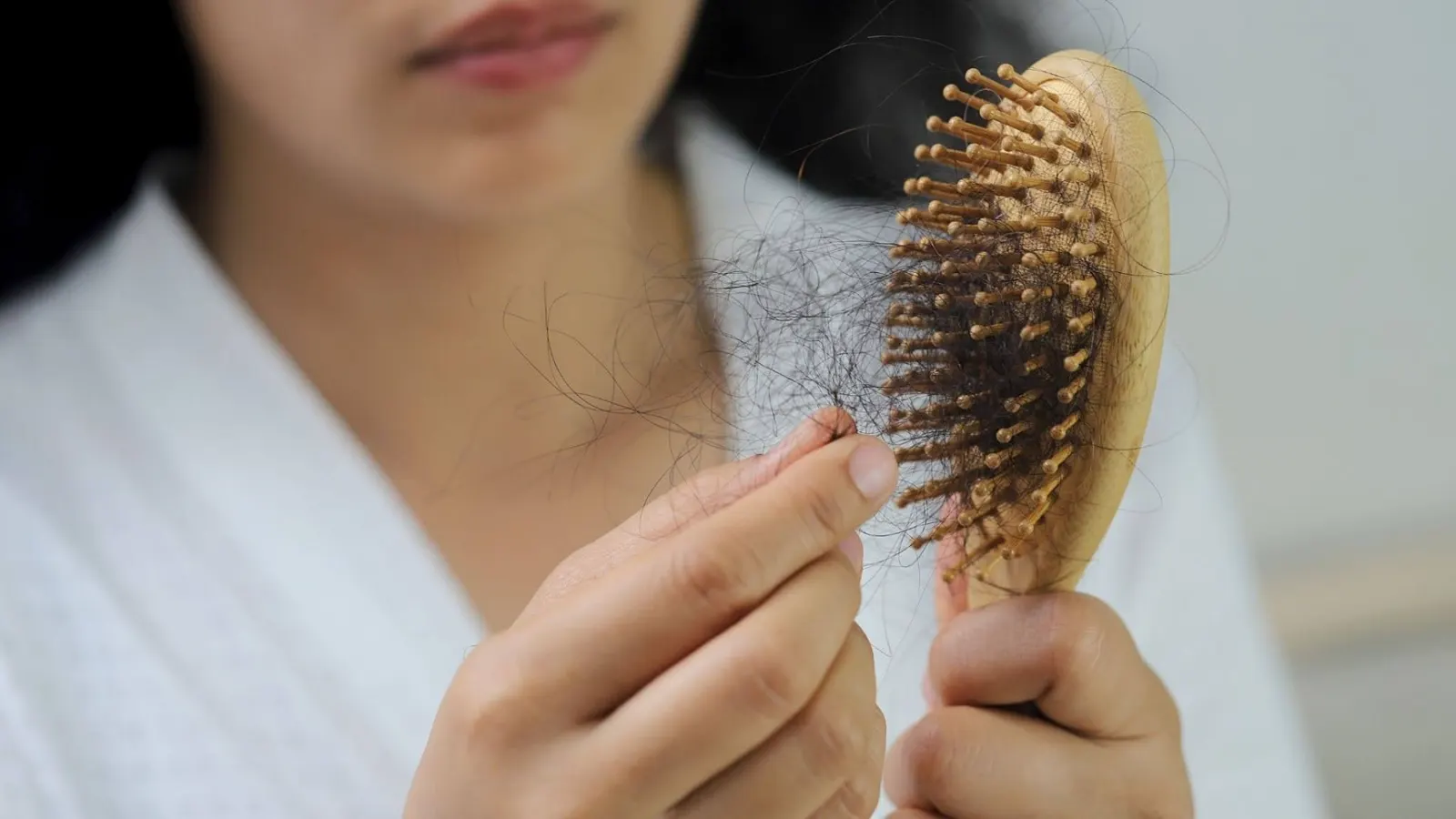 Person holding a wooden hairbrush with shed hair strands